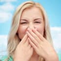Woman covering her nose with hands, reacting to unpleasant smell, symbolizing HVAC system odors and maintenance issues.