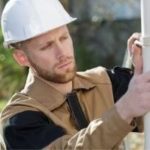 Construction worker in safety gear assembling equipment outdoors for The Meridian Company home services in Lansing, MI.