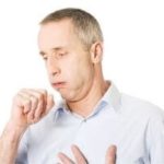 Man coughing in a light blue shirt against a neutral background, representing health issues relevant to home maintenance.