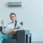 Young woman on a sofa using a notepad in a modern room with air conditioning, representing The Meridian Company services.