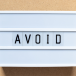 Lightbox display with the word "AVOID" in black on white, against a brown background, relating to HVAC caution.