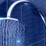 Modern showerhead atop textured blue tiles, showcasing continuous water flow for home improvement. - The Meridian Company.