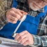 Man with tools measuring sewer system plans for plumbing maintenance at The Meridian Company.