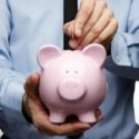 Person in formal attire inserting money into a pink piggy bank, representing financial planning for home services.