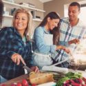 Three individuals cooking in a modern kitchen with utensils and vegetables, highlighting home service expertise.