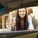 Two young girls in a car, one waving, promoting friendly community interactions. HVAC and home service maintenance focus.