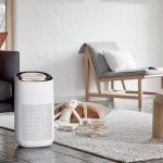 Modern air purifier in a clean, minimalistic living space with a couch, coffee table, and rug.