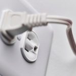 Close-up of an electrical plug in a white socket, highlighting a functional design by The Meridian Company.