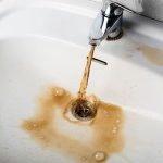 Contaminated sink water with bubbles and sediment, showcasing plumbing issues at The Meridian Company.