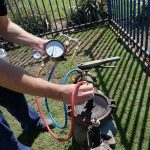 Individual servicing machinery with a pressure gauge and hoses, representing The Meridian Company's home services.