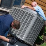 Two men installing an HVAC unit outside a residential building in Lansing, MI, focusing on home maintenance services.