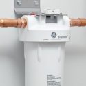 Water filter unit with copper tubing, white body, and GE logo for home maintenance and purification services.
