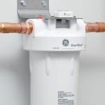 GE water filter system with white housing and copper pipes, supporting Lansing home improvement services.