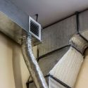 Metallic air ducts and ventilation system with textured ducting and grille vent for HVAC efficiency.
