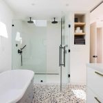 Modern bathroom with glass shower enclosure and freestanding bathtub, featuring minimalist design and neutral tones.