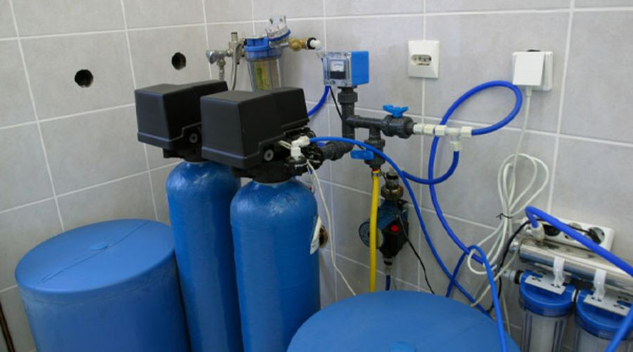 Water treatment equipment with blue tanks and pipes for efficient plumbing by The Meridian Company in Lansing, MI.