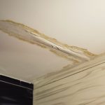 Damaged ceiling with peeling paint and exposed material indicating water damage—The Meridian Company's plumbing services.